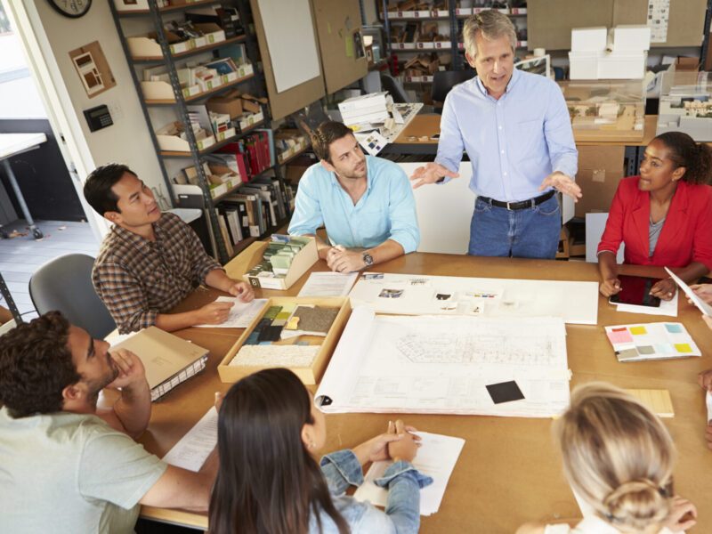 Group Of Architects Sitting Around Table Having Meeting